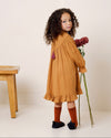 Early Sunday, Penelope Dress in Almond, made from Dyed Cotton Double Gauze fabric, featuring Hand-embroidered floral motifs, shown in a back view of model wearing it