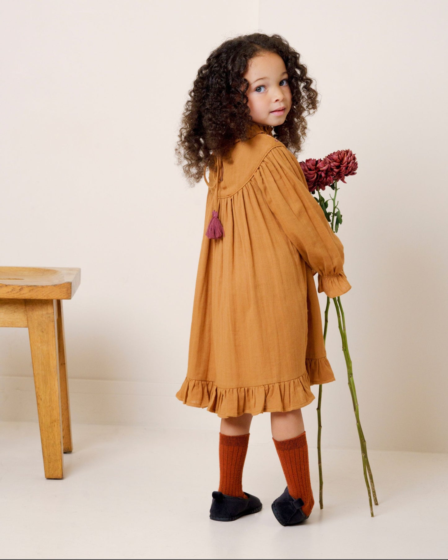 Early Sunday, Penelope Dress in Almond, made from Dyed Cotton Double Gauze fabric, featuring Hand-embroidered floral motifs, shown in a back view of model wearing it