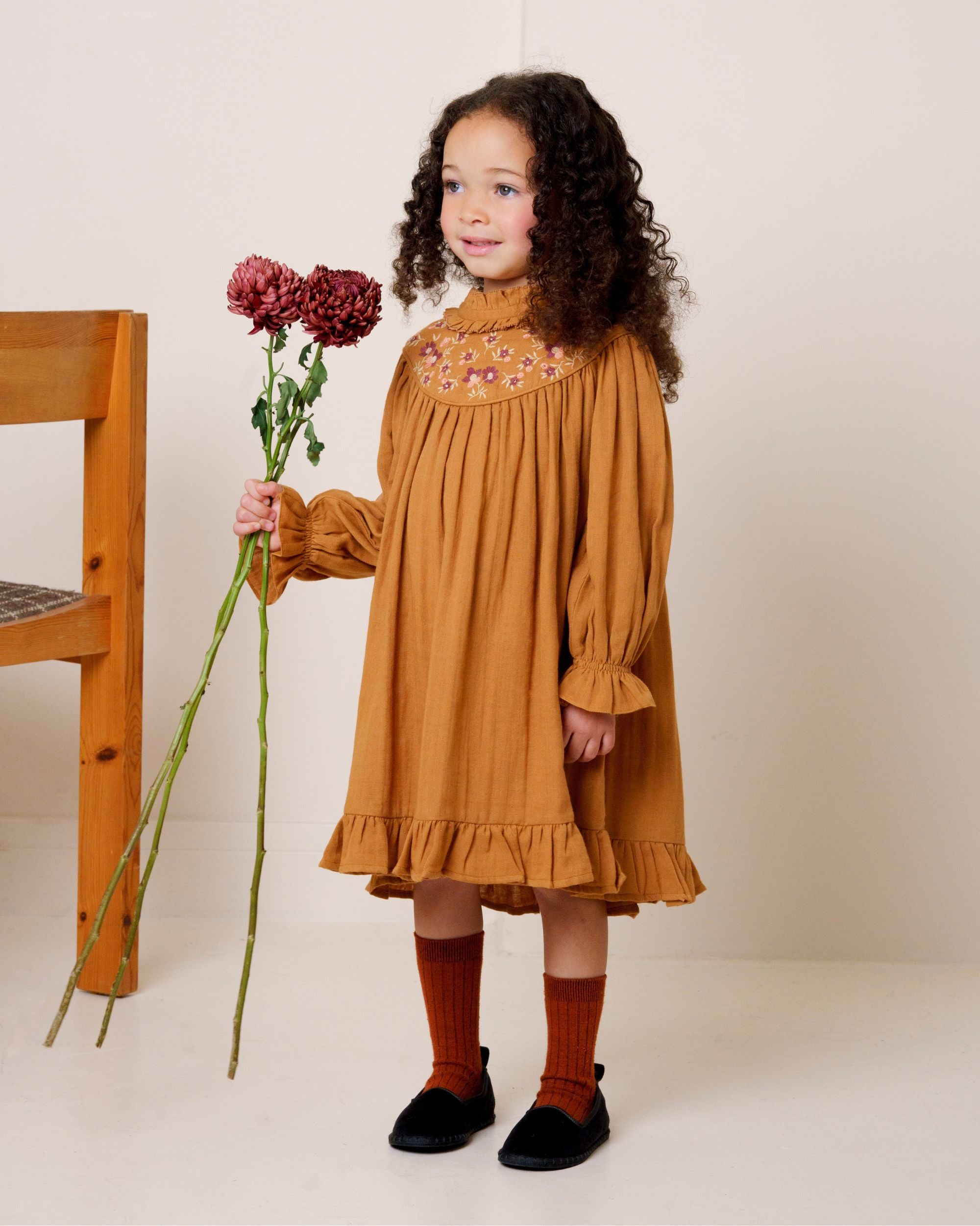Early Sunday, Penelope Dress in Almond, made from Dyed Cotton Double Gauze fabric, featuring Hand-embroidered floral motifs, shown in a front view of a model wearing it in a studio setting