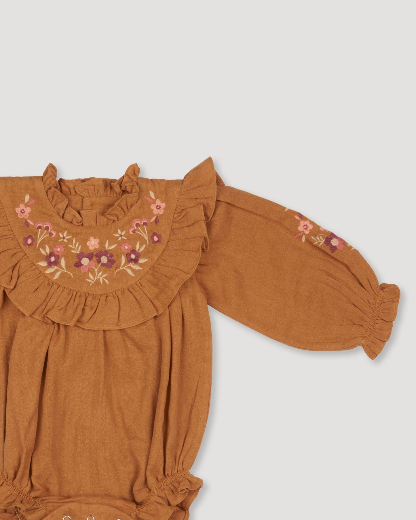 Early Sunday, Pippa Baby Bubble Romper in Almond color, made from Dyed Cotton Double Gauze fabric, featuring beautiful embroidery with frilly neck, shown in a closeup flat-lay view