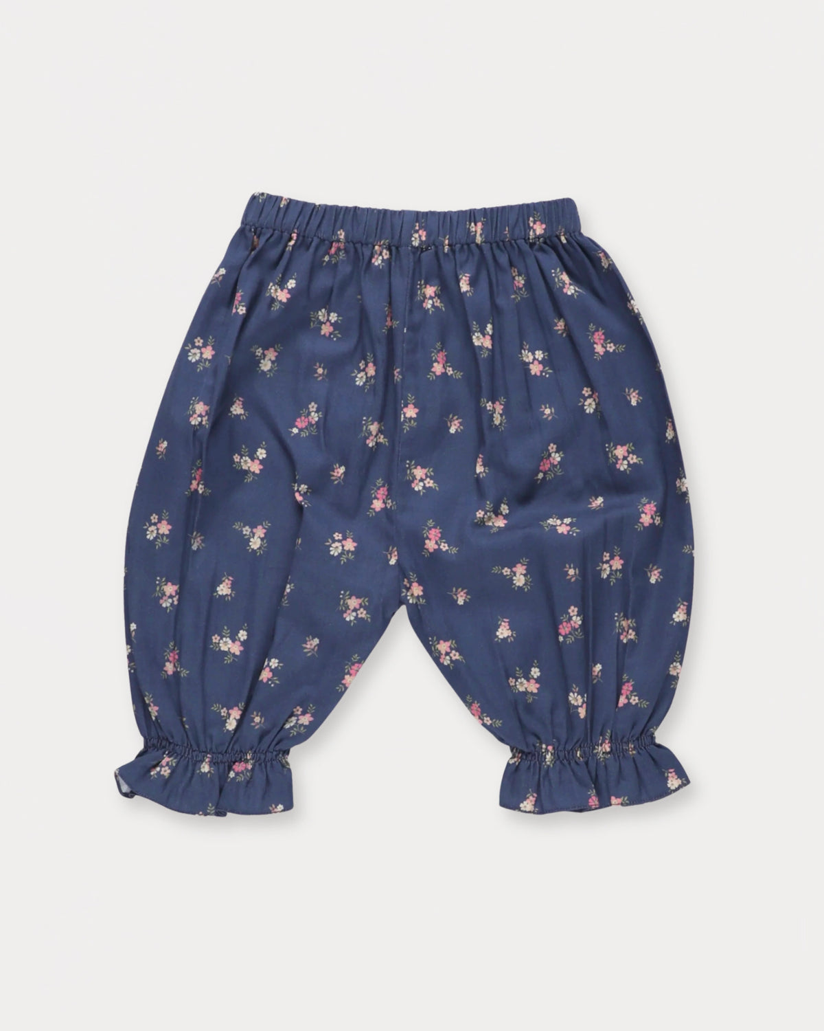 Early Sunday, Poppy Baby Bloomer Trousers in Ditsy Bouquet Navy, made from Printed Cotton Satin fabric, featuring an elasticated waistband & ruffled cuffs at the ankles, shown in a back flat-lay view
