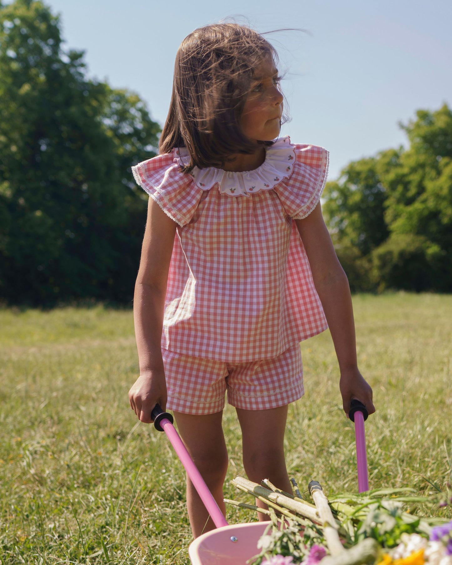 Early Sunday, Roman Cotton Gingham Check Short in Peony color, made from 100% Cotton fabric, featuring a relaxed silhouette with a comfortable elastic waistband, shown in a front view of model wearing outdoors
