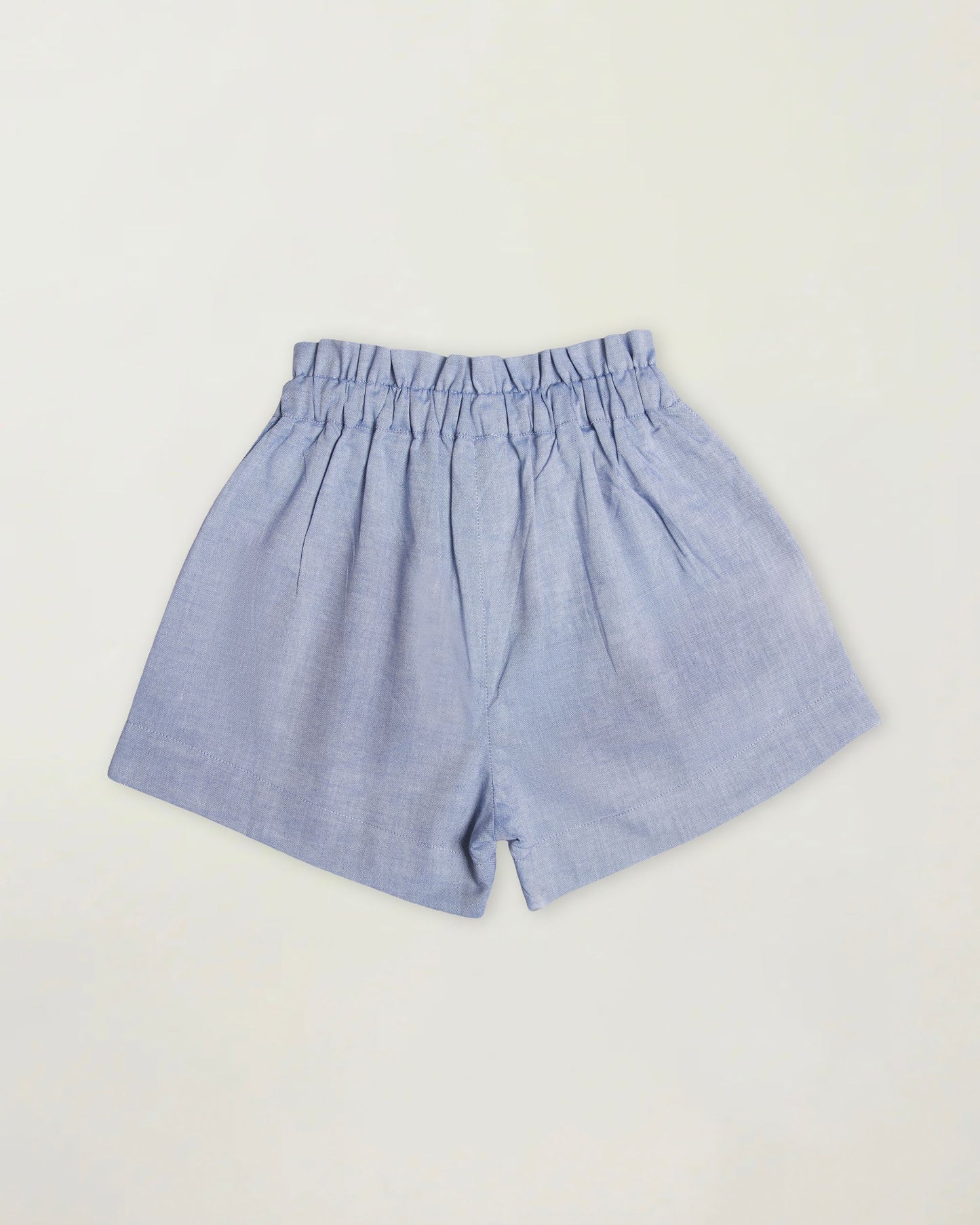 Early Sunday, Roman Short in Summer Sky color, made from 100% Cotton Chambray fabric, featuring a relaxed fit with an elastic waistband & beautiful embroidery, shown in a back flat-lay view