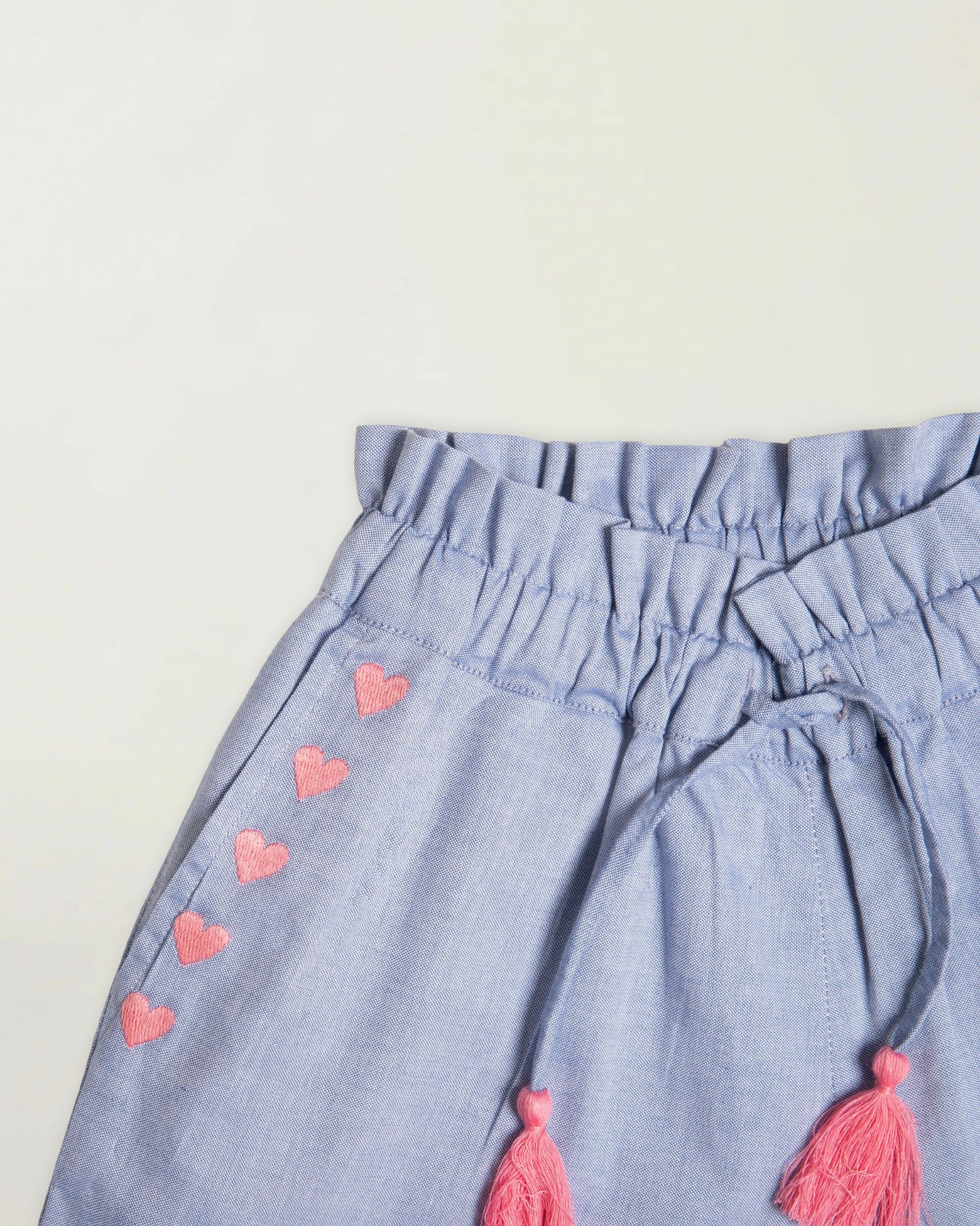Early Sunday, Roman Short in Summer Sky color, made from 100% Cotton Chambray fabric, featuring a relaxed fit with an elastic waistband & beautiful embroidery, shown in a closeup flat-lay view