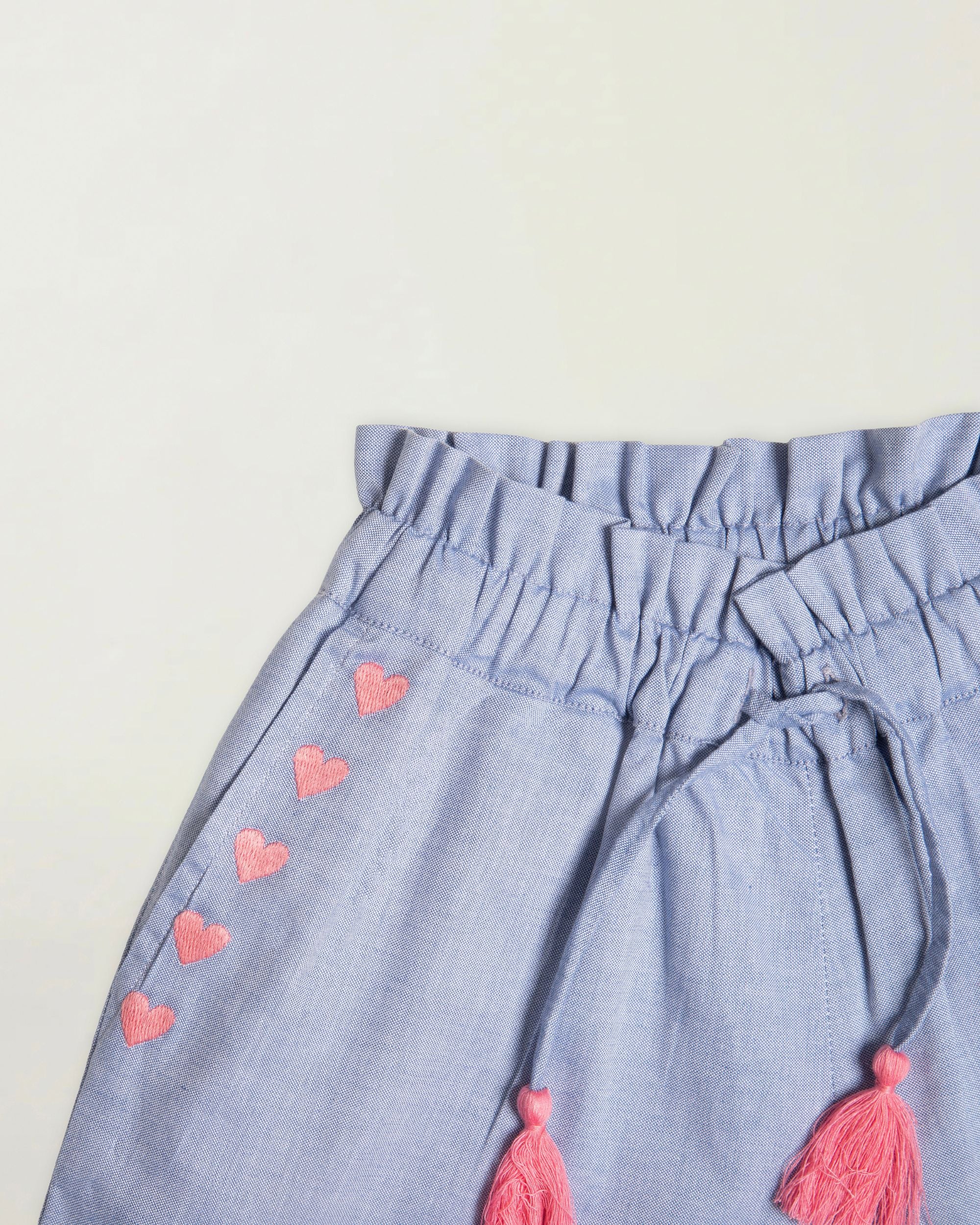 Early Sunday, Roman Short in Summer Sky color, made from 100% Cotton Chambray fabric, featuring a relaxed fit with an elastic waistband & beautiful embroidery, shown in a closeup flat-lay view