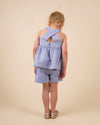 Early Sunday, Roman Short in Summer Sky color, made from 100% Cotton Chambray fabric, featuring a relaxed fit with an elastic waistband & beautiful embroidery, shown in a back view of a model wearing it in a studio setting
