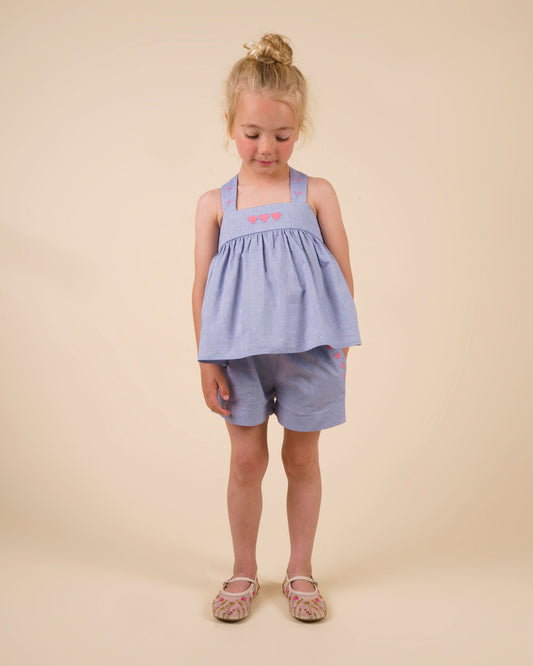 Early Sunday, Roman Short in Summer Sky color, made from 100% Cotton Chambray fabric, featuring a relaxed fit with an elastic waistband & beautiful embroidery, shown in a front view of a model wearing it in a studio setting