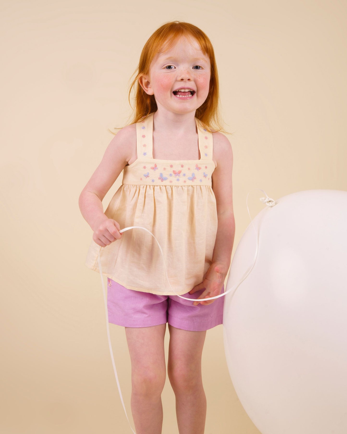 Early Sunday, Roman Short in Lilac color, made from 70% Cotton 30% Linen fabric, featuring a relaxed fit with an elastic waistband & beautiful embroidery, shown in a front view of a model wearing it in a studio setting