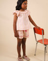 Early Sunday, Roman Short in Pink Strips print, made from 70% Cotton 30% Linen fabric, featuring a relaxed fit with an elastic waistband & striped design, shown in an angled view of a model wearing it in a studio setting