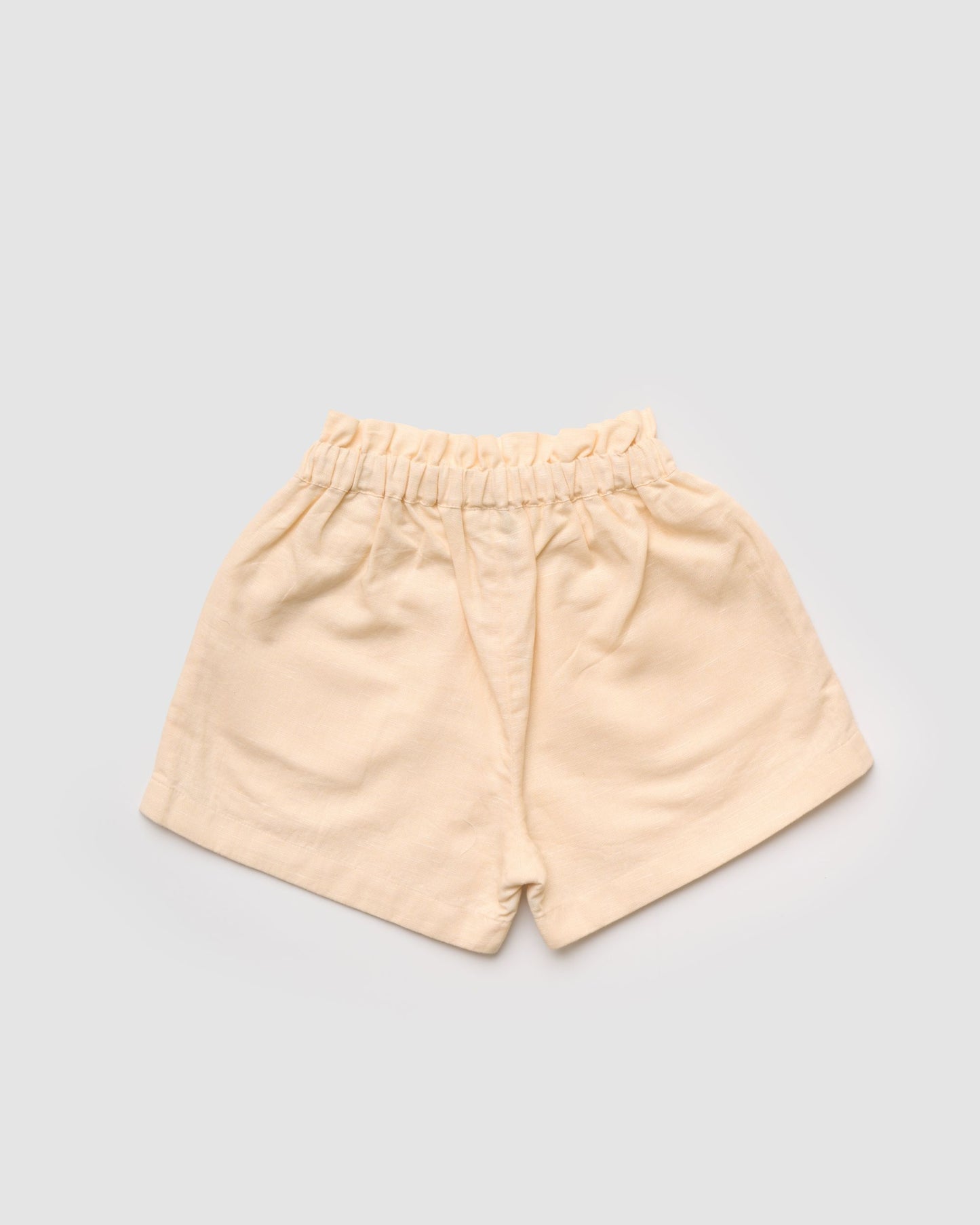 Early Sunday, Roman Short in Sand color, made from 70% Cotton 30% Linen fabric, featuring a relaxed fit with an elastic waistband & beautiful embroidery, shown in a back flat-lay view