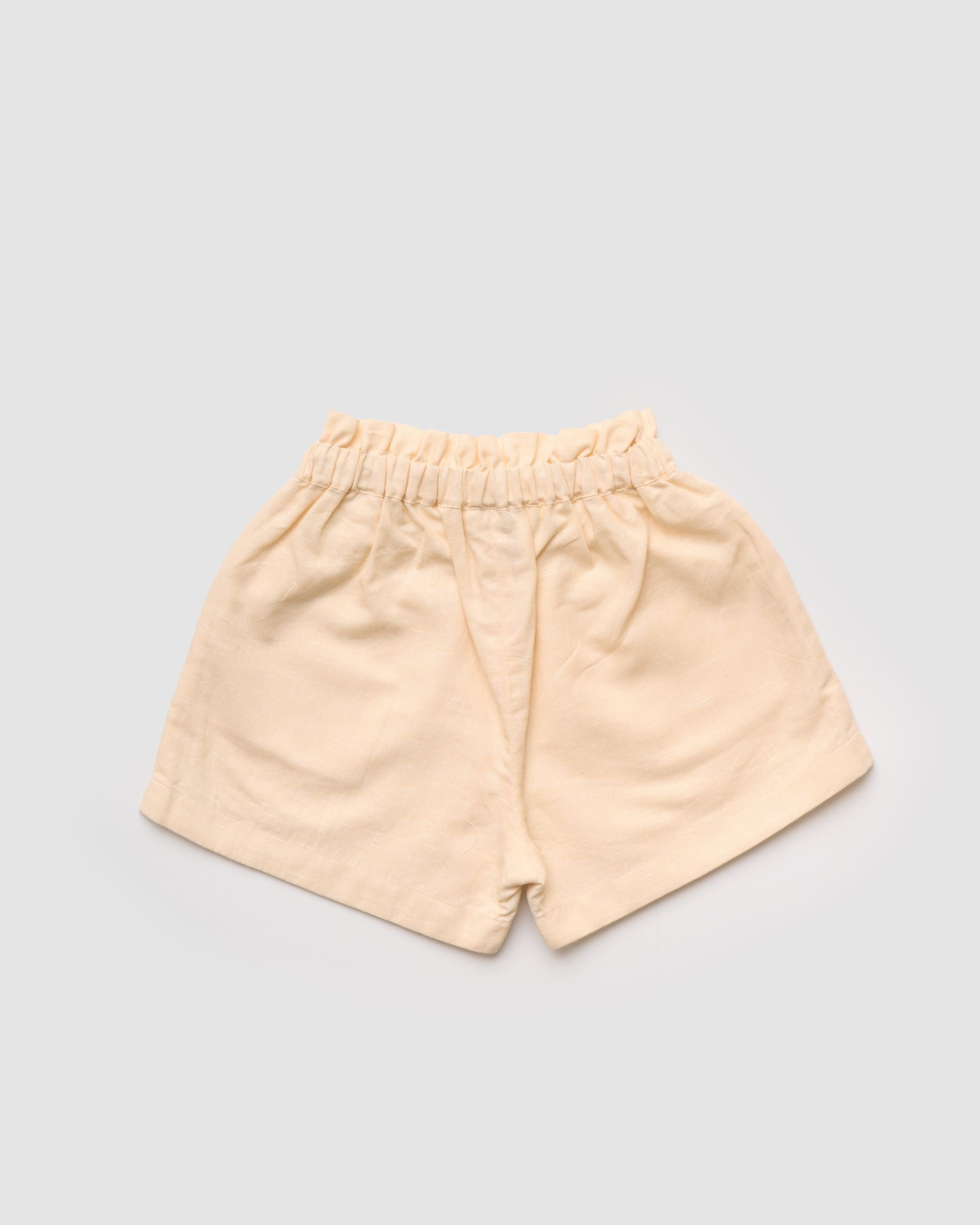 Early Sunday, Roman Short in Sand color, made from 70% Cotton 30% Linen fabric, featuring a relaxed fit with an elastic waistband & beautiful embroidery, shown in a back flat-lay view