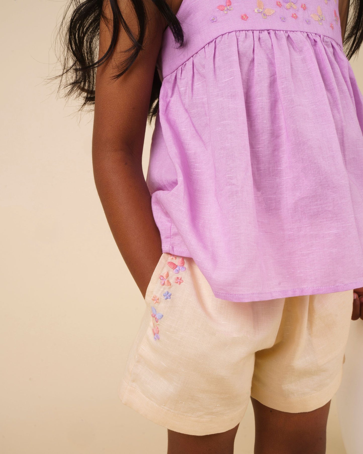 Early Sunday, Roman Short in Sand color, made from 70% Cotton 30% Linen fabric, featuring a relaxed fit with an elastic waistband & beautiful embroidery, shown in a close-up shot of a model wearing it during a studio shoot