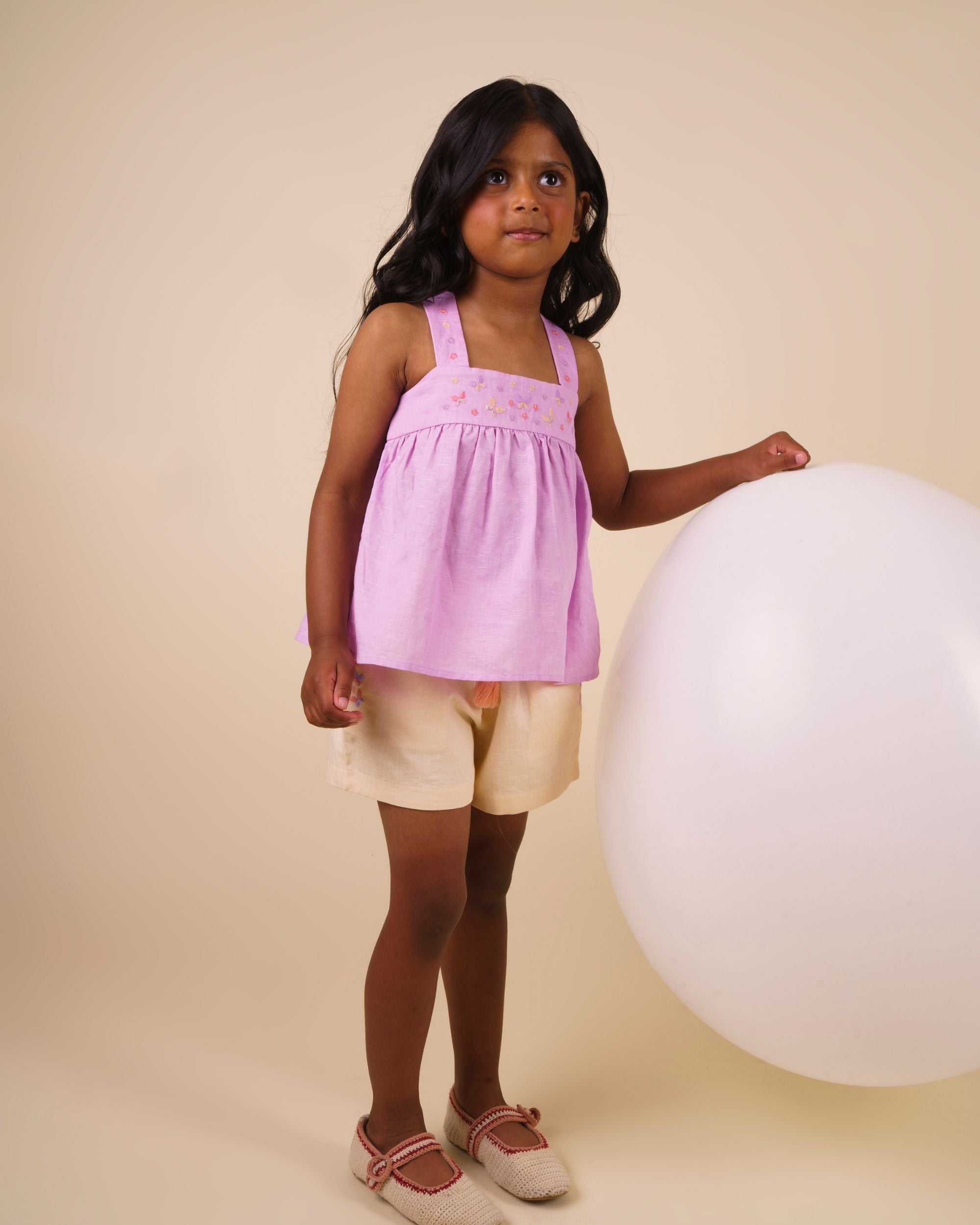 Early Sunday, Roman Short in Sand color, made from 70% Cotton 30% Linen fabric, featuring a relaxed fit with an elastic waistband & beautiful embroidery, shown in a front view of a model wearing it in a studio setting