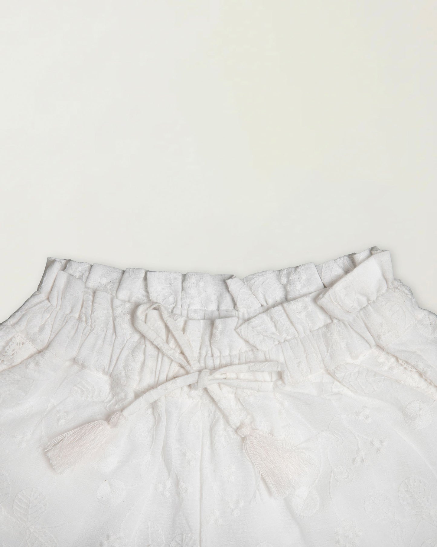 Early Sunday, Roman Short in Ivory color, made from All Over Embroidery fabric, featuring a relaxed fit with an elastic waistband & beautiful embroidery, shown in a closeup flat-lay view