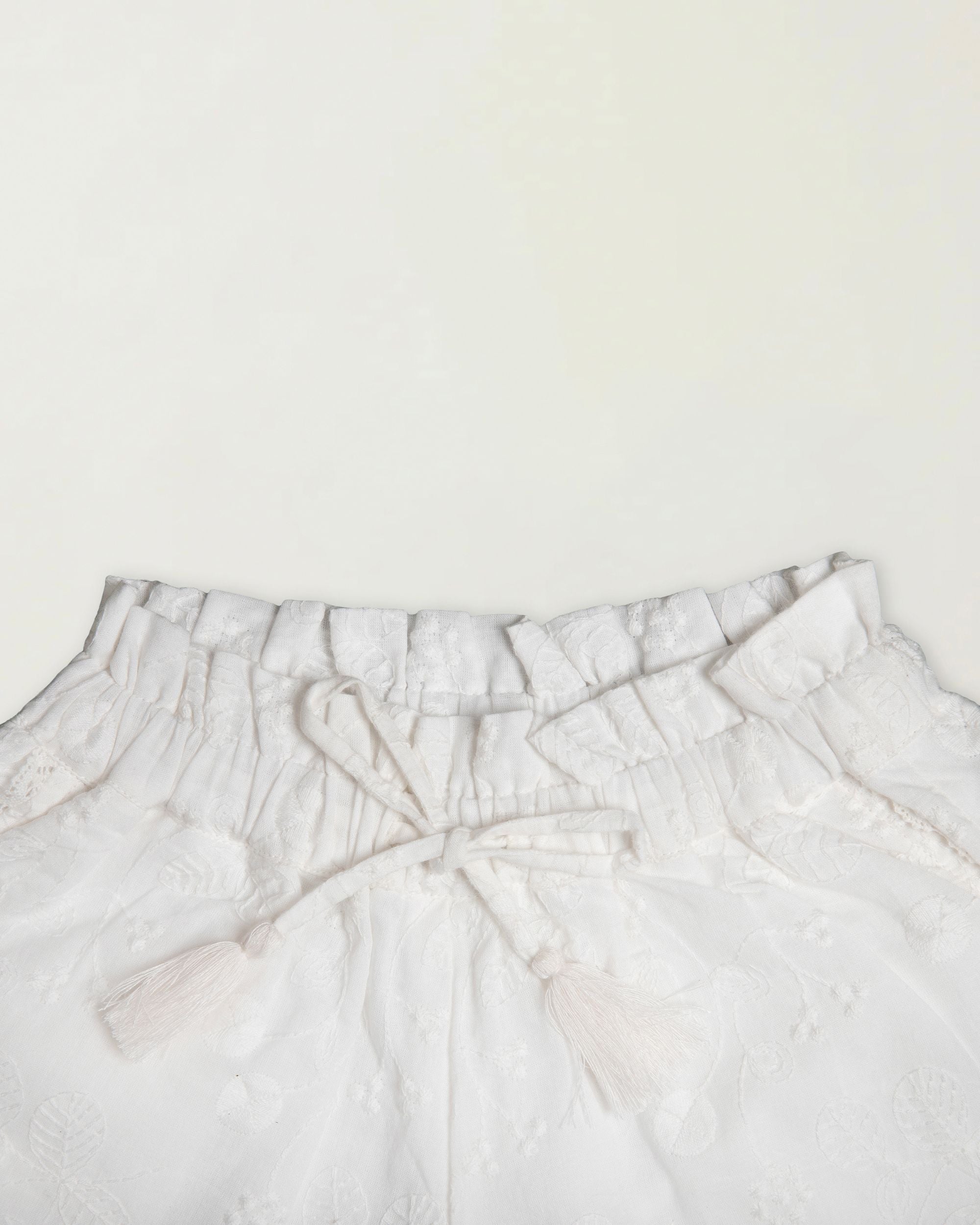 Early Sunday, Roman Short in Ivory color, made from All Over Embroidery fabric, featuring a relaxed fit with an elastic waistband & beautiful embroidery, shown in a closeup flat-lay view
