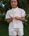 Early Sunday, Roman Short in Ivory color, made from All Over Embroidery fabric, featuring a relaxed fit with an elastic waistband & beautiful embroidery, shown in a front view of model wearing outdoors