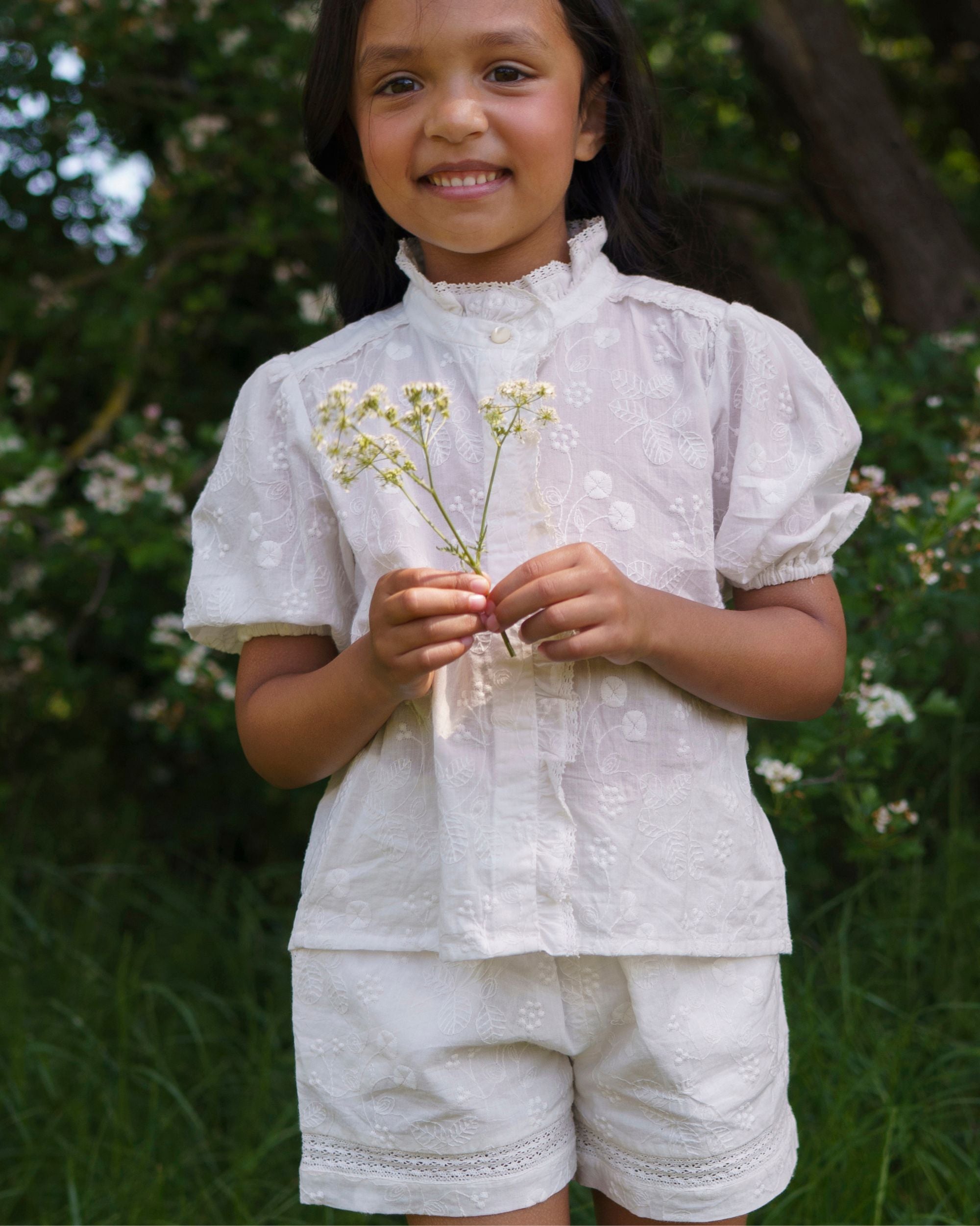 Early Sunday, Roman Short in Ivory color, made from All Over Embroidery fabric, featuring a relaxed fit with an elastic waistband & beautiful embroidery, shown in a front view of model wearing outdoors