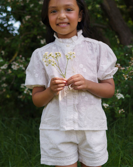 Early Sunday, Roman Short in Ivory color, made from All Over Embroidery fabric, featuring a relaxed fit with an elastic waistband & beautiful embroidery, shown in a front view of model wearing outdoors