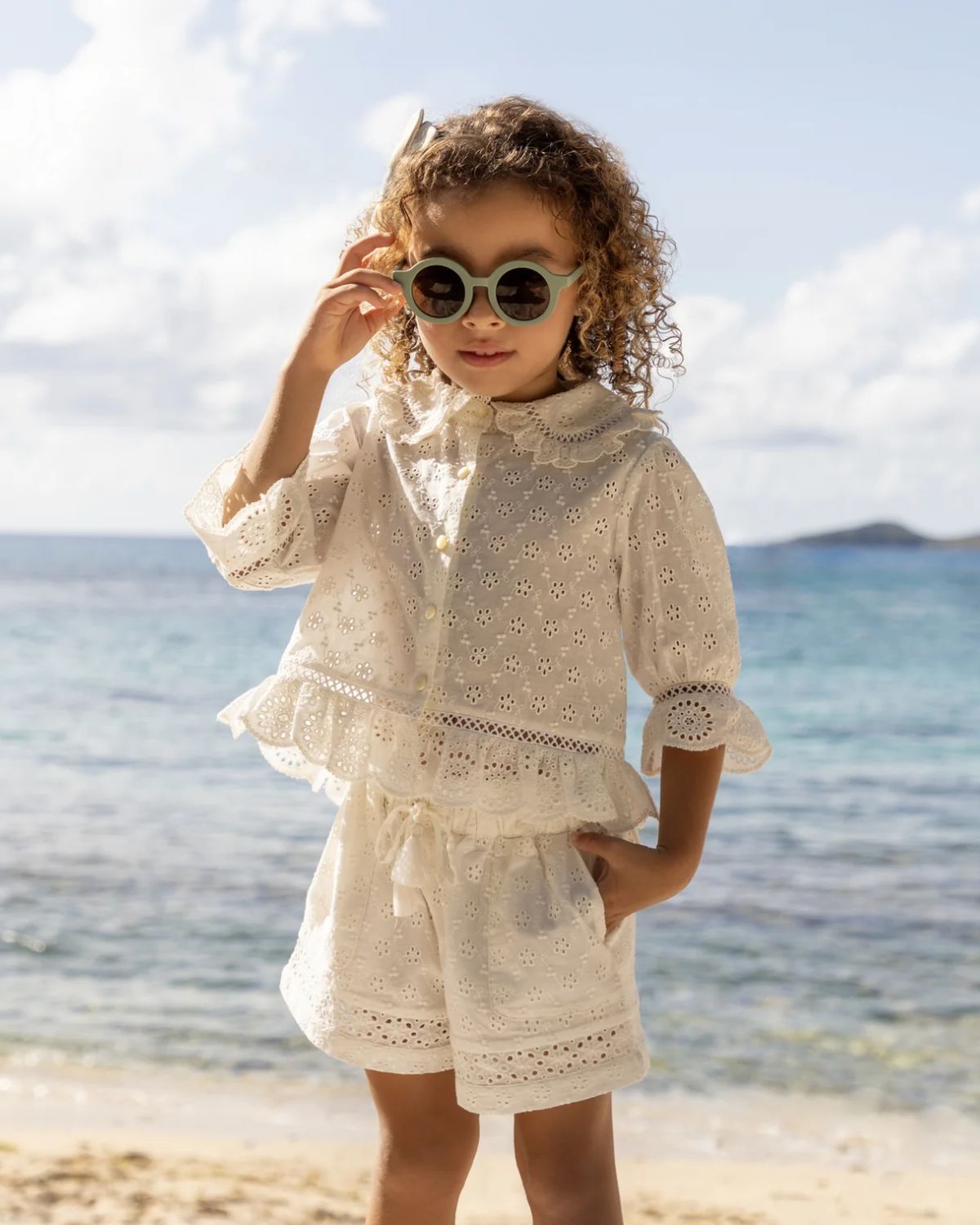 Early Sunday, Roman Shorts in Ivory color, made from All-Over Eyelet Embroidered Cotton Schifflie fabric, featuring relaxed fit with delicate finishes, combining style and functionality, shown in a front view of model wearing it