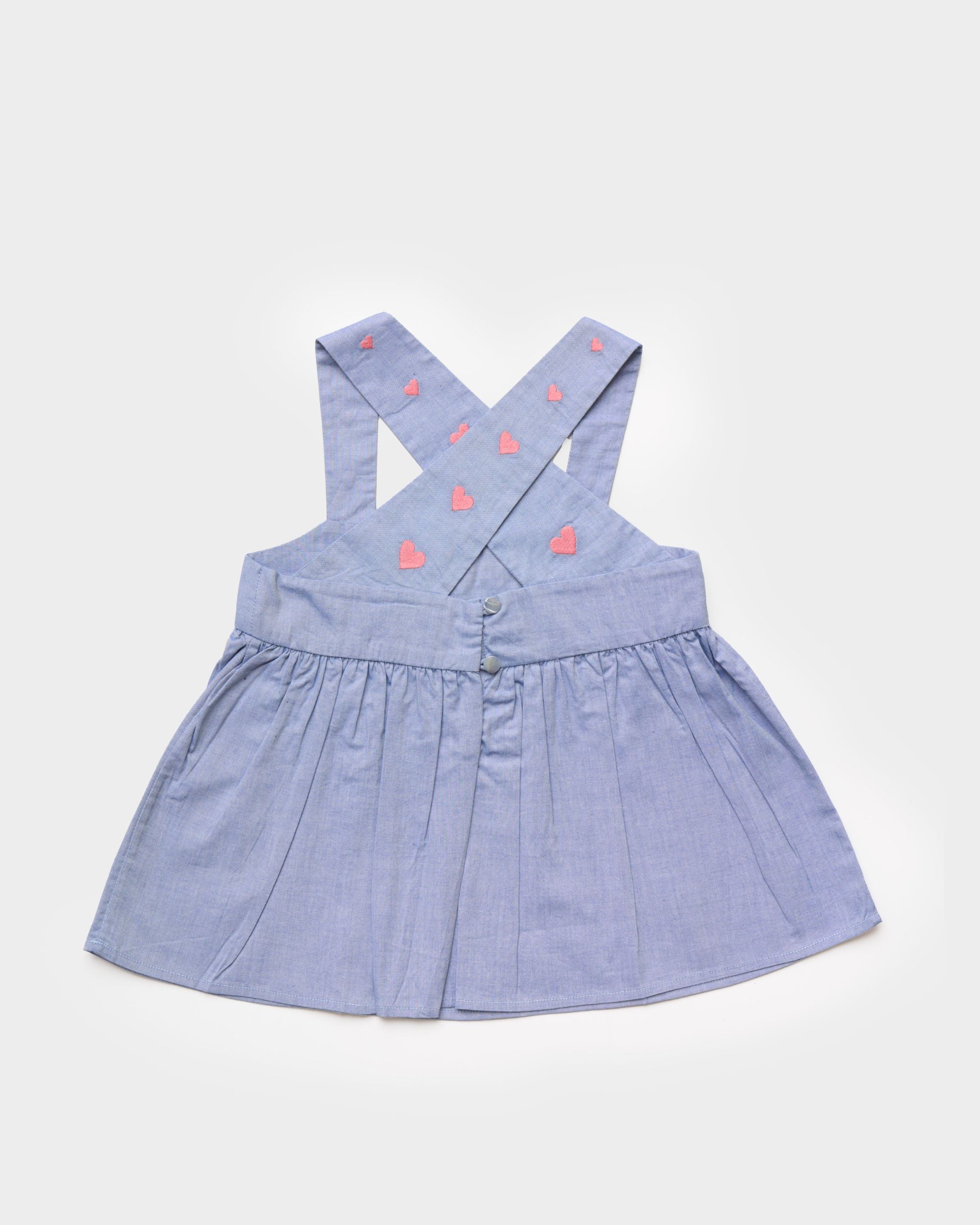 Early Sunday, Romy Blouse in Summer Sky color, made from  100% Cotton Chambray fabric, featuring a sleeveless design with cross-back straps, a gathered waist & a beautiful embroidery, shown in a back flat-lay view