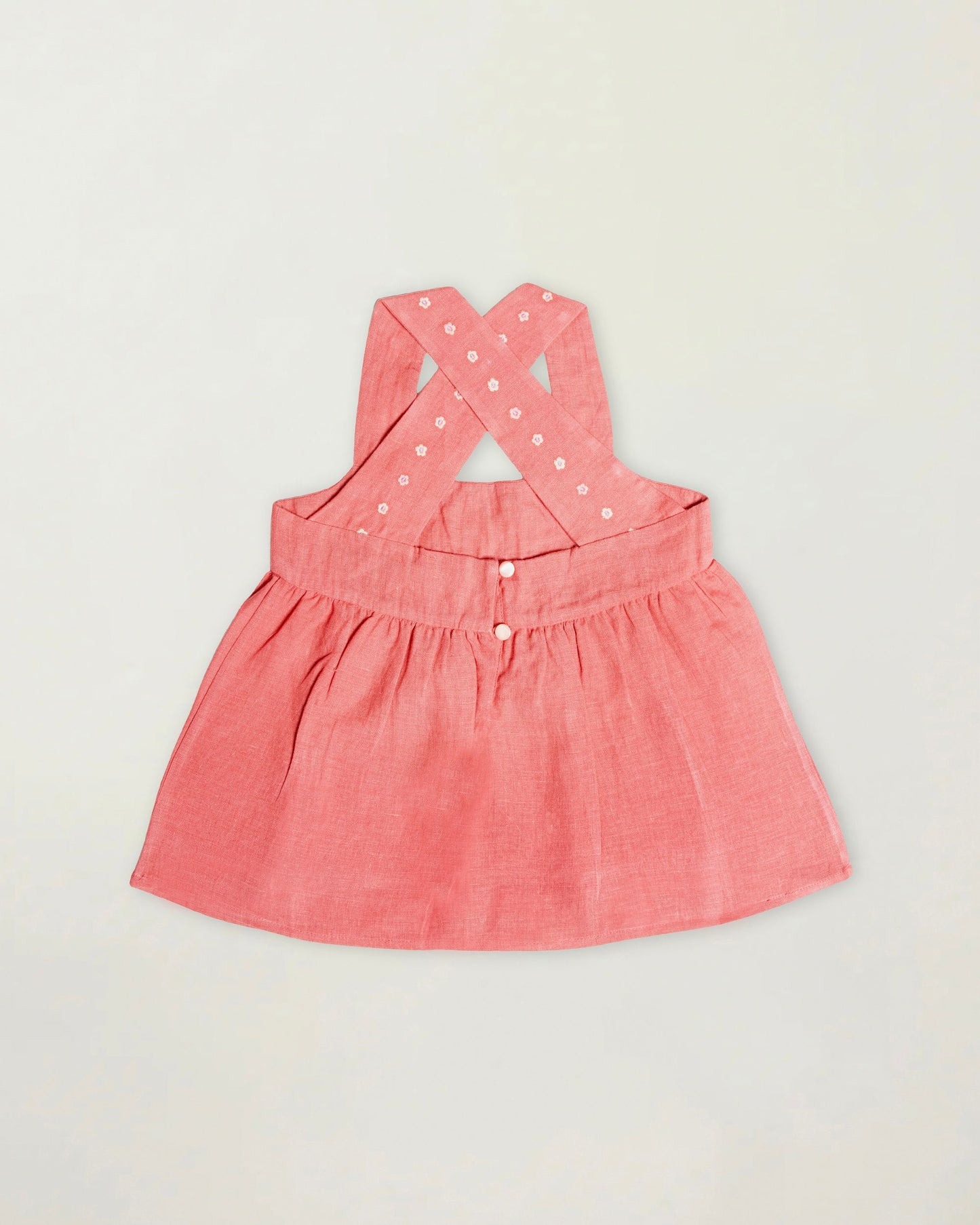 Early Sunday, Romy Blouse in Peony color, made from 70% Cotton 30% Linen fabric, featuring a sleeveless design with cross-back straps, a gathered waist & a beautiful embroidery, shown in a back flat-lay view