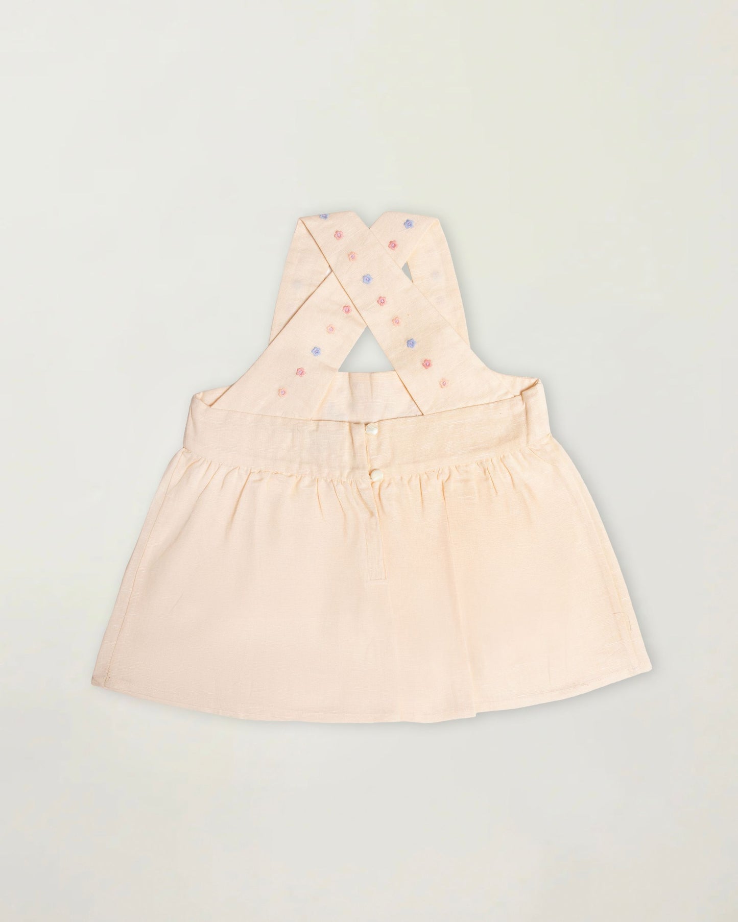 Early Sunday, Romy Blouse in Sand color, made from 70% Cotton 30% Linen fabric, featuring a sleeveless design with cross-back straps, a gathered waist & a beautiful embroidery, shown in a back flat-lay view