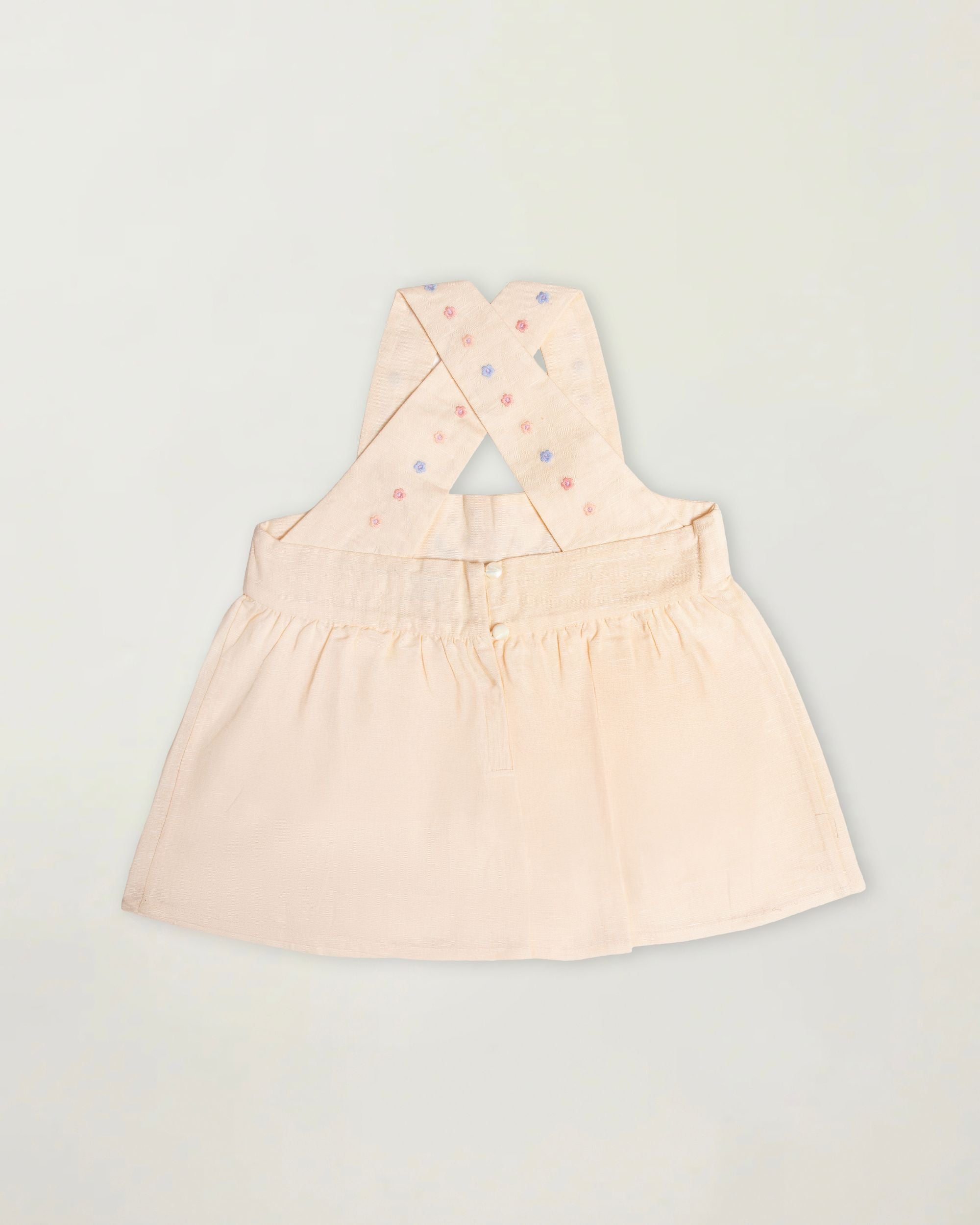 Early Sunday, Romy Blouse in Sand color, made from 70% Cotton 30% Linen fabric, featuring a sleeveless design with cross-back straps, a gathered waist & a beautiful embroidery, shown in a back flat-lay view