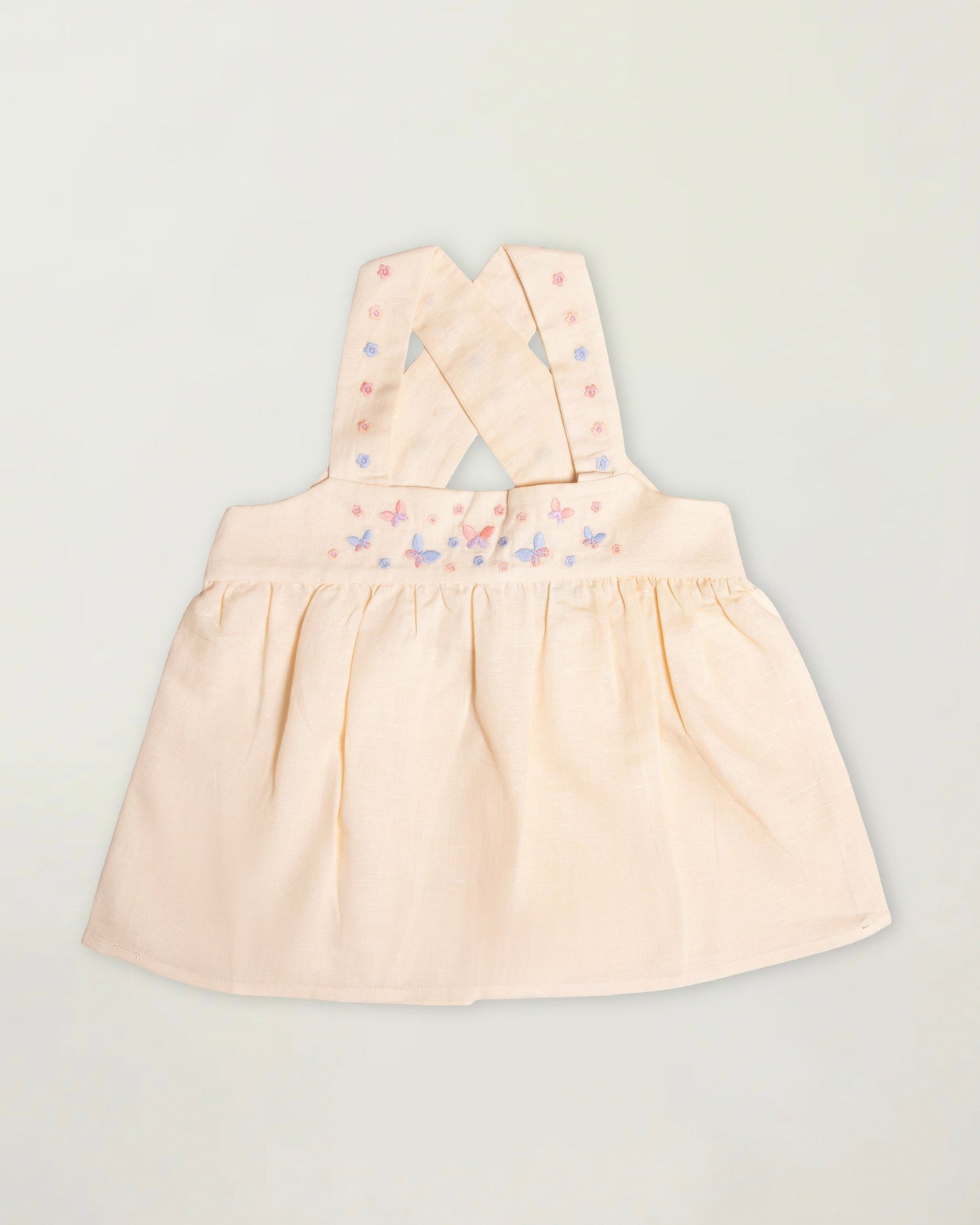Early Sunday, Romy Blouse in Sand color, made from 70% Cotton 30% Linen fabric, featuring a sleeveless design with cross-back straps, a gathered waist & a beautiful embroidery, shown in a front flat-lay view