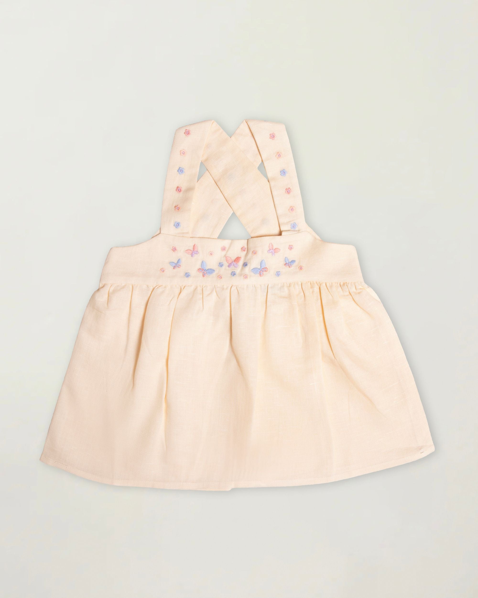 Early Sunday, Romy Blouse in Sand color, made from 70% Cotton 30% Linen fabric, featuring a sleeveless design with cross-back straps, a gathered waist & a beautiful embroidery, shown in a front flat-lay view
