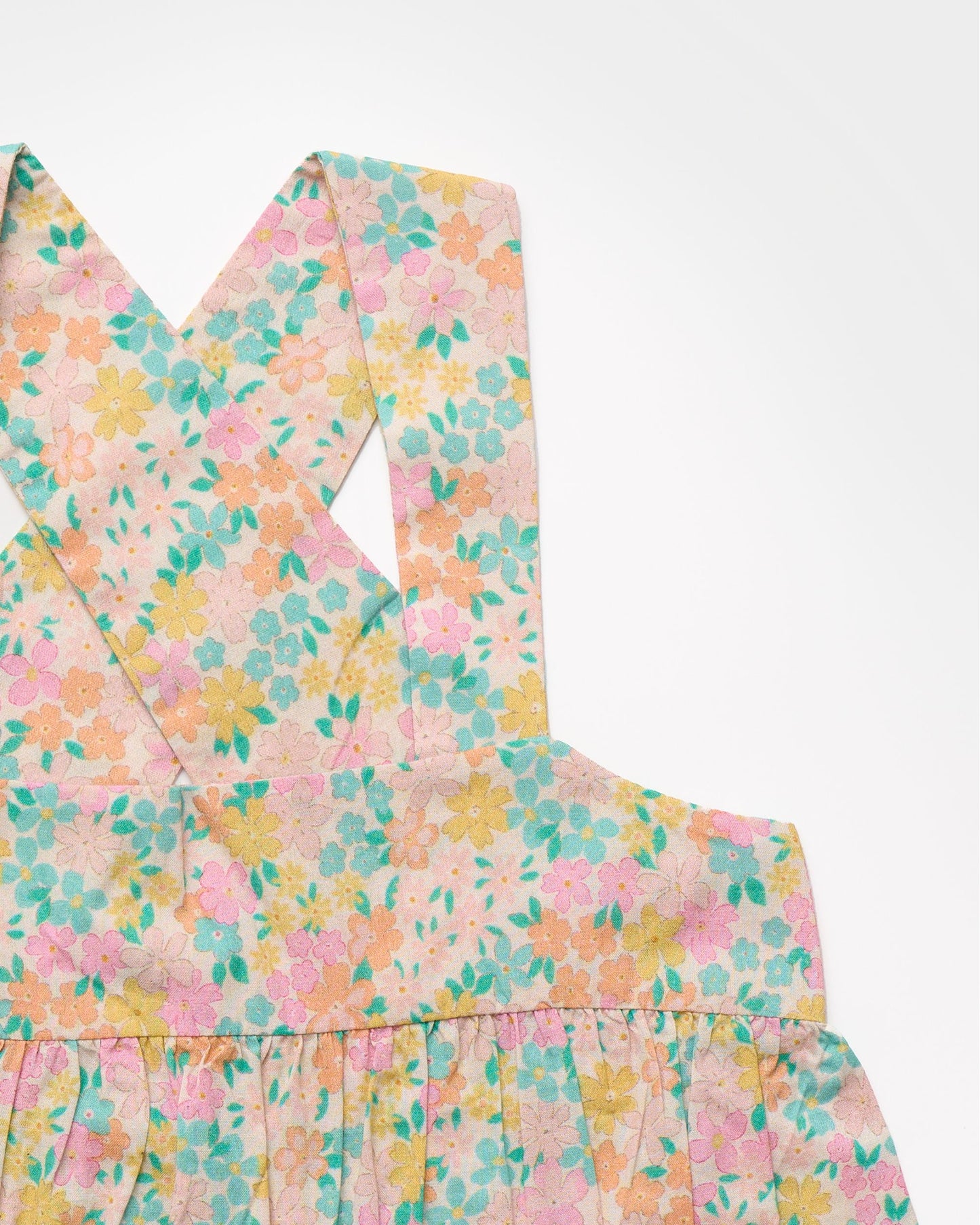Early Sunday, Romy Blouse in Emma Floral Mint color, made from Organic Printed 60s Cotton Cambric fabric, featuring a sleeveless design with cross-back straps, a gathered waist & a soft flared silhouette, shown in a closeup flat-lay view