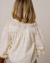 Early Sunday, Rosa Blouse in Hazelnut Cream, made from All-Over Embroidered Cotton Cambric fabric, featuring Frilled neckline detailed with a lace collar for a vintage touch, shown in a back view of model wearing it
