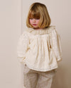 Early Sunday, Rosa Blouse in Hazelnut Cream, made from All-Over Embroidered Cotton Cambric fabric, featuring Frilled neckline detailed with a lace collar for a vintage touch, shown in a front view of a model wearing it in a studio setting