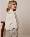 Early Sunday, Rosa Blouse in Hazelnut Cream, made from All-Over Embroidered Cotton Cambric fabric, featuring Frilled neckline detailed with a lace collar for a vintage touch, shown in a side view of model wearing it