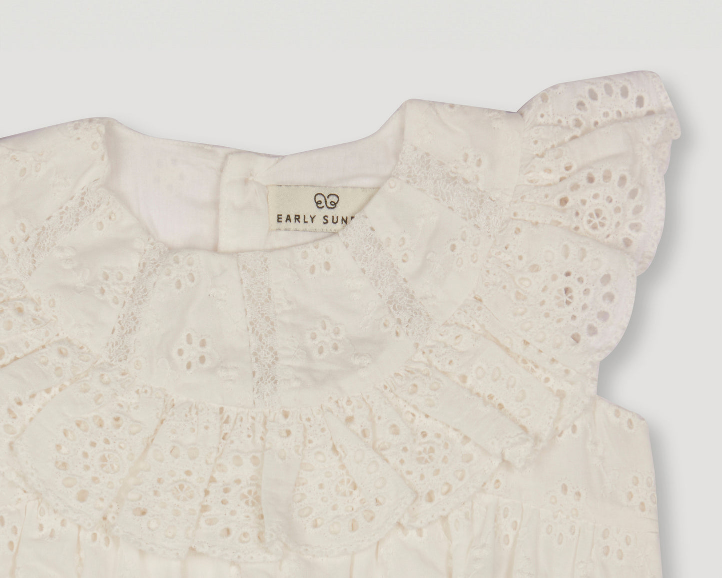 Early Sunday, Rose Baby Bubble Romper in Ivory color, made from All-Over Eyelet Embroidered Cotton Schifflie fabric, featuring gathered bubble silhouette for a cute and comfortable fit, with a relaxed design that allows for ease of movement, shown in a closeup flat-lay view