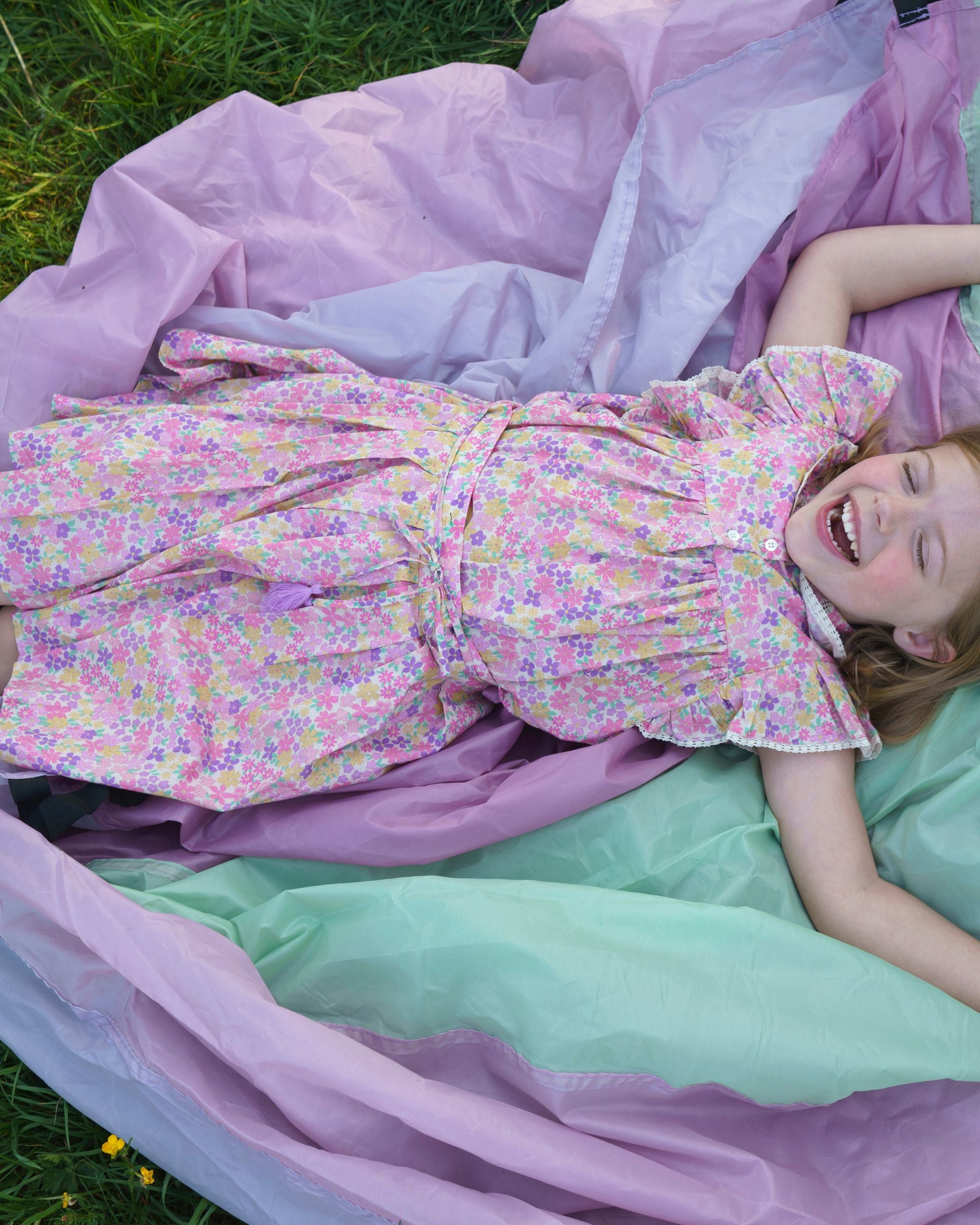 Early Sunday, Ruth Skirt in Emma Floral Purple color, made from Organic Printed Cotton Cambric fabric, featuring a flared silhouette with an elastic waistband & floral design, shown in a close up shot of model playing outdoors