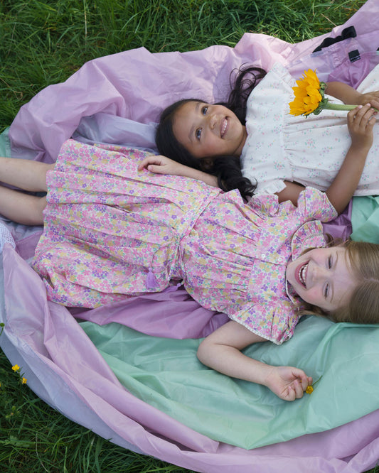 Early Sunday, Ruth Skirt in Emma Floral Purple color, made from Organic Printed Cotton Cambric fabric, featuring a flared silhouette with an elastic waistband & floral design, shown in a close up shot of models playing outdoors