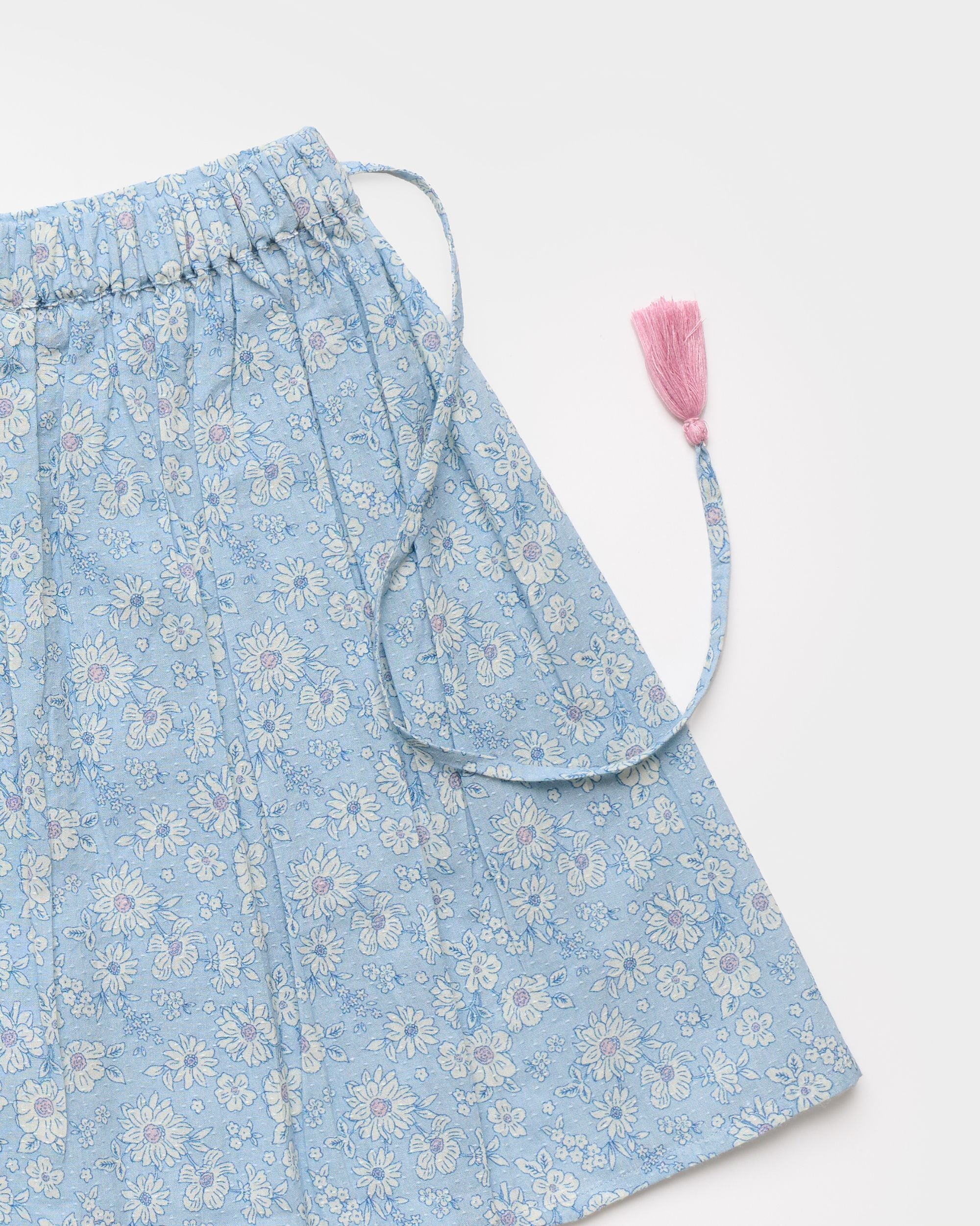 Early Sunday, Ruth Skirt in Tonal Floral Blue color, made from Printed Cotton Tiny Swiss Dobby fabric, featuring a flared silhouette with an elastic waistband & floral design, shown in a closeup flat-lay view