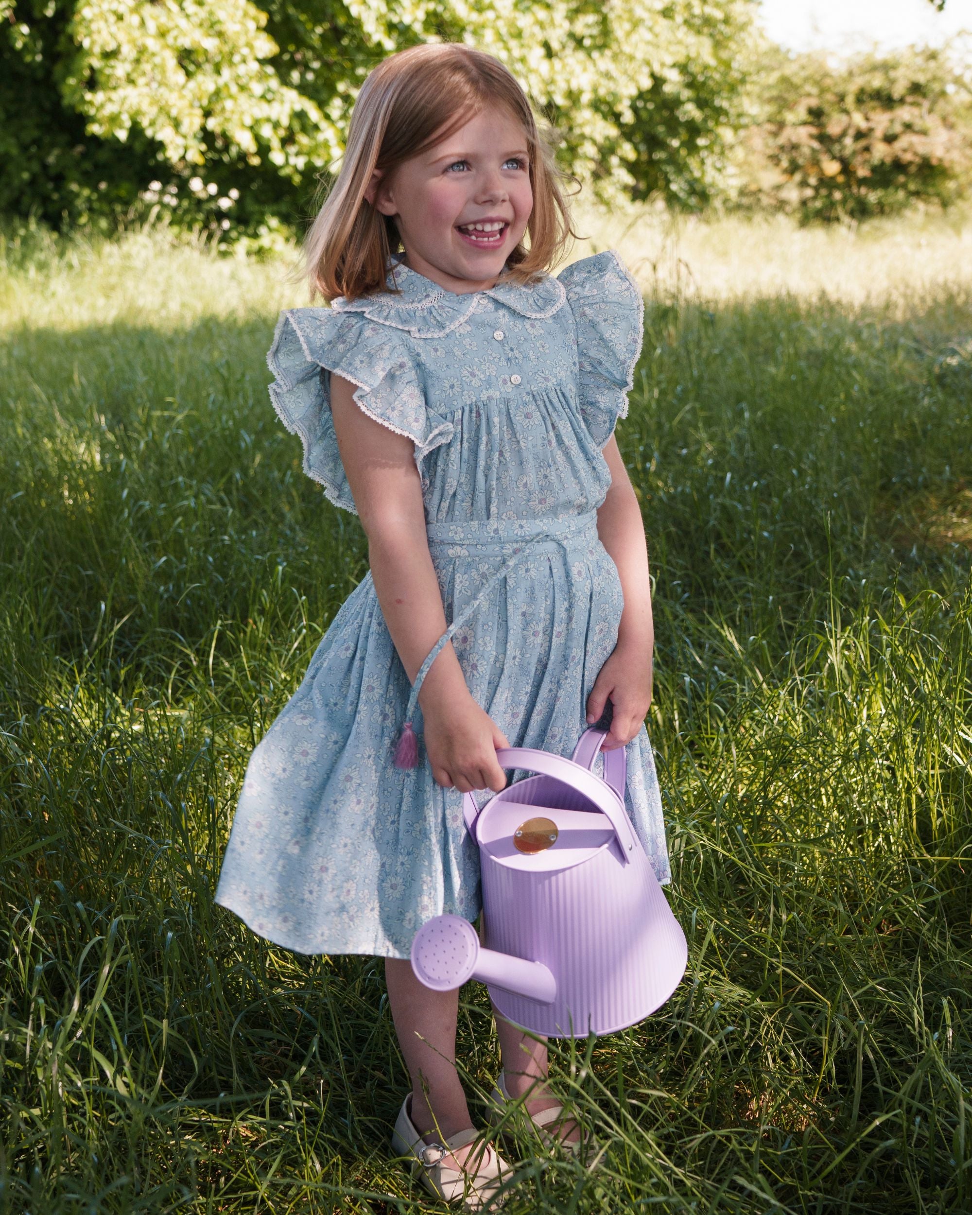 Early Sunday, Ruth Skirt in Tonal Floral Blue color, made from Printed Cotton Tiny Swiss Dobby fabric, featuring a flared silhouette with an elastic waistband & floral design, shown in a front view of model wearing outdoors