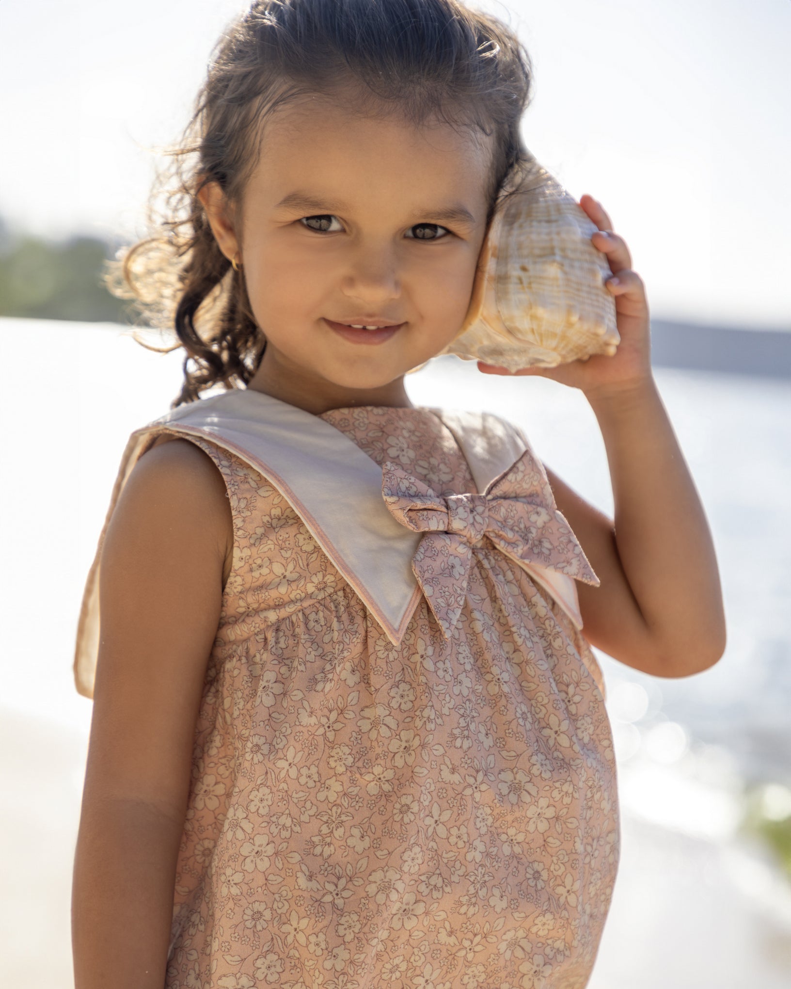 Early Sunday, Sabrina Dress in Garden Flowers print, made from Printed Cotton Cambric fabric, featuring flattering fit with delicate finishes, combining style and functionality for an effortlessly elegant look, shown in a an angled view of a model wearing outdoors