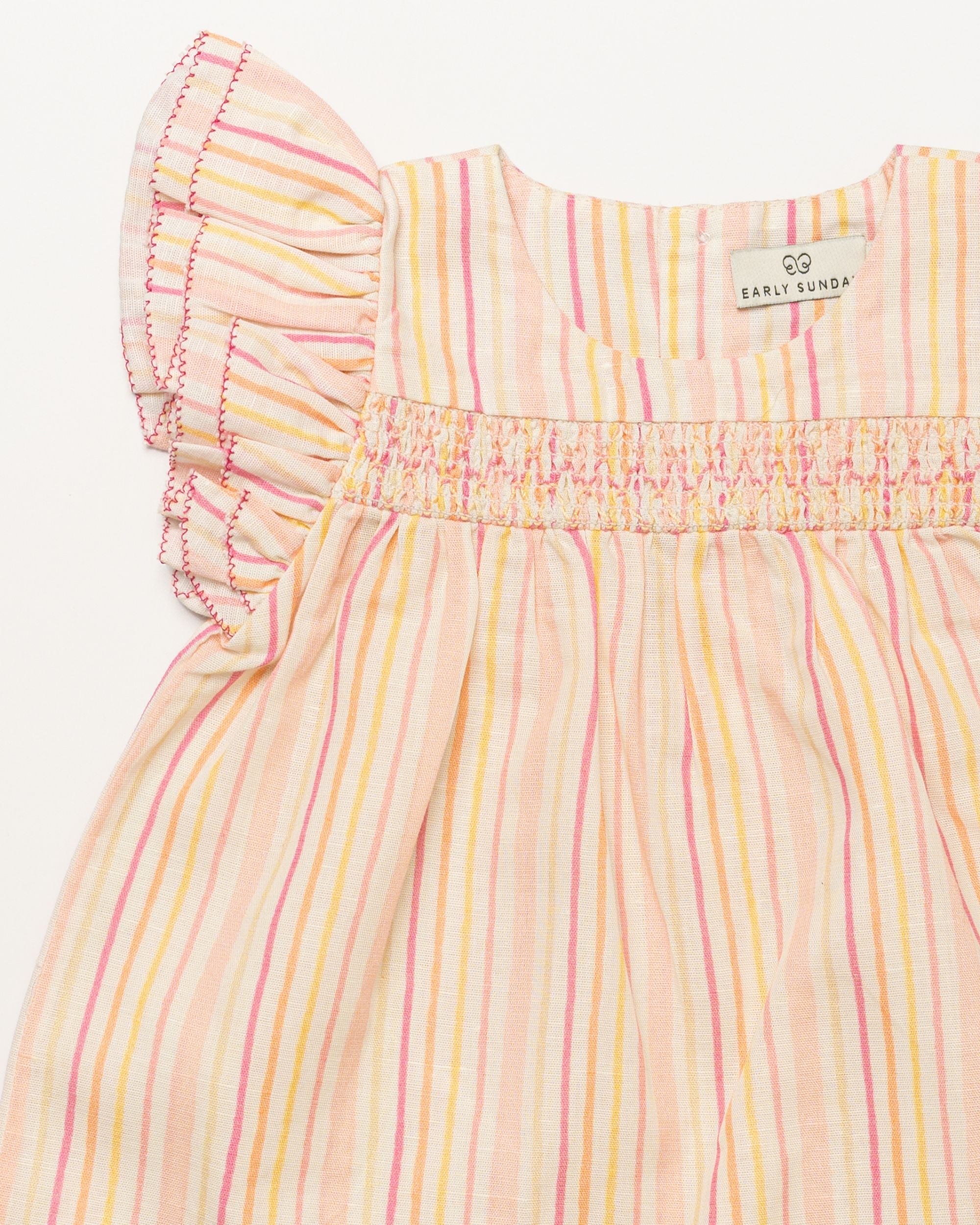 Early Sunday, Sienna Baby Dress & Bloomer Set in Pink Stripes print, made from 70% Cotton 30% Linen fabric, featuring a relaxed fit with smocked chest band & frilled sleeves, shown in a closeup flat-lay view