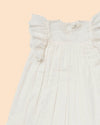 Early Sunday, Sita Dress in Ivory color, made from Tiny Swiss Dobby fabric, featuring a sleeveless design with wide shoulder straps & a delicate lace yoke, shown in a closeup flat-lay view