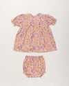Early Sunday, Sofia Baby Dress & Bloomer Set in Emma Floral Purple color, made from 100% Organic Cotton 60s Cambric fabric, featuring short sleeves with peter pan collar, shown in a back flat-lay view