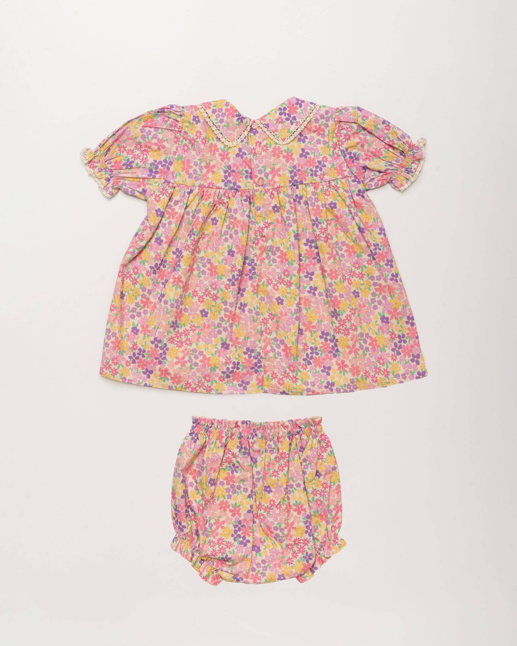 Early Sunday, Sofia Baby Dress & Bloomer Set in Emma Floral Purple color, made from 100% Organic Cotton 60s Cambric fabric, featuring short sleeves with peter pan collar, shown in a back flat-lay view