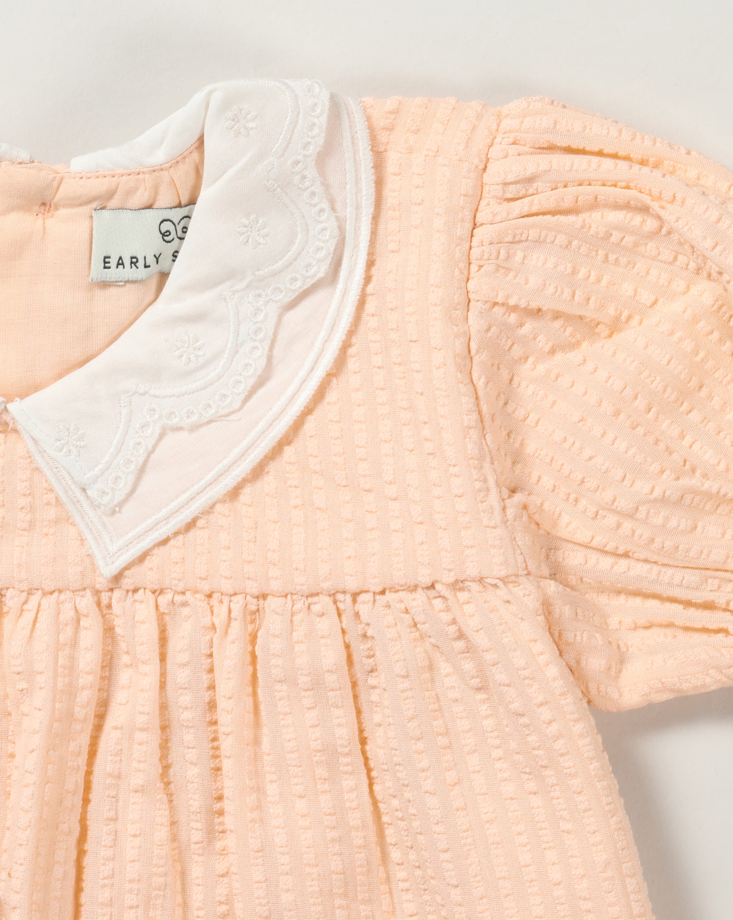 Early Sunday, Sukie Baby Dress & Bloomer in Warm Sand color, made from Cotton Seersucker fabric, featuring flared dress with a relaxed fit for ease of movement, matching bloomer with an elasticated waistband for comfort and flexibility., shown in a closeup flat-lay view