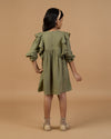 Early Sunday, Suzanne Dress in Dried Leaf, made from Cotton Double Gauze fabric, featuring classic silhouette with floral embroidery around the yoke and ruffle detailing, shown in a back view of model wearing it