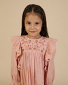 Early Sunday, Suzanne Dress in Dusty Pink, made from Cotton Double Gauze fabric, featuring classic silhouette with floral embroidery around the yoke and ruffle detailing, shown in a close-up shot of a model wearing it during a studio shoot