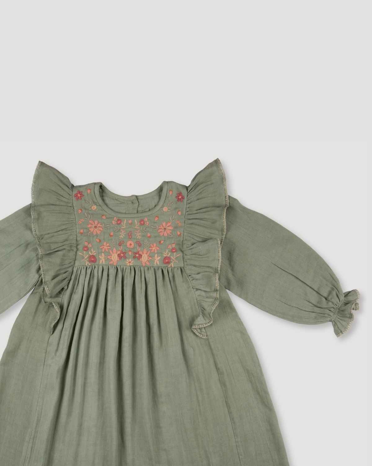 Early Sunday, Suzanne Dress in Halcyon Green, made from Cotton Double Gauze fabric, featuring classic silhouette with floral embroidery around the yoke and ruffle detailing, shown in a closeup flat-lay view