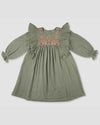 Early Sunday, Suzanne Dress in Halcyon Green, made from Cotton Double Gauze fabric, featuring classic silhouette with floral embroidery around the yoke and ruffle detailing, shown in a front flat-lay view