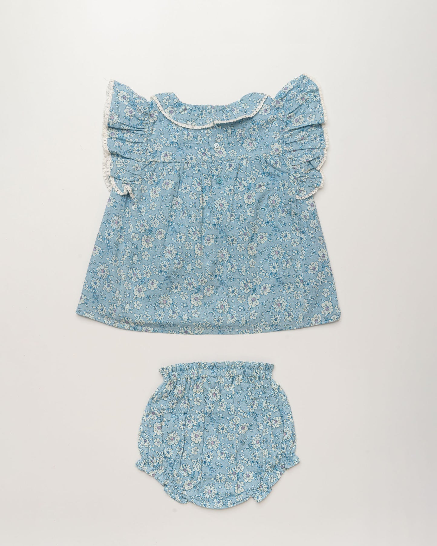 Early Sunday, Vicky Baby Dress & Bloomer Set in Tonal Floral Blue color, made from 100% Cotton Swiss Dobby Tiny Dots fabric, featuring a floral print with lace borders, shown in a back flat-lay view