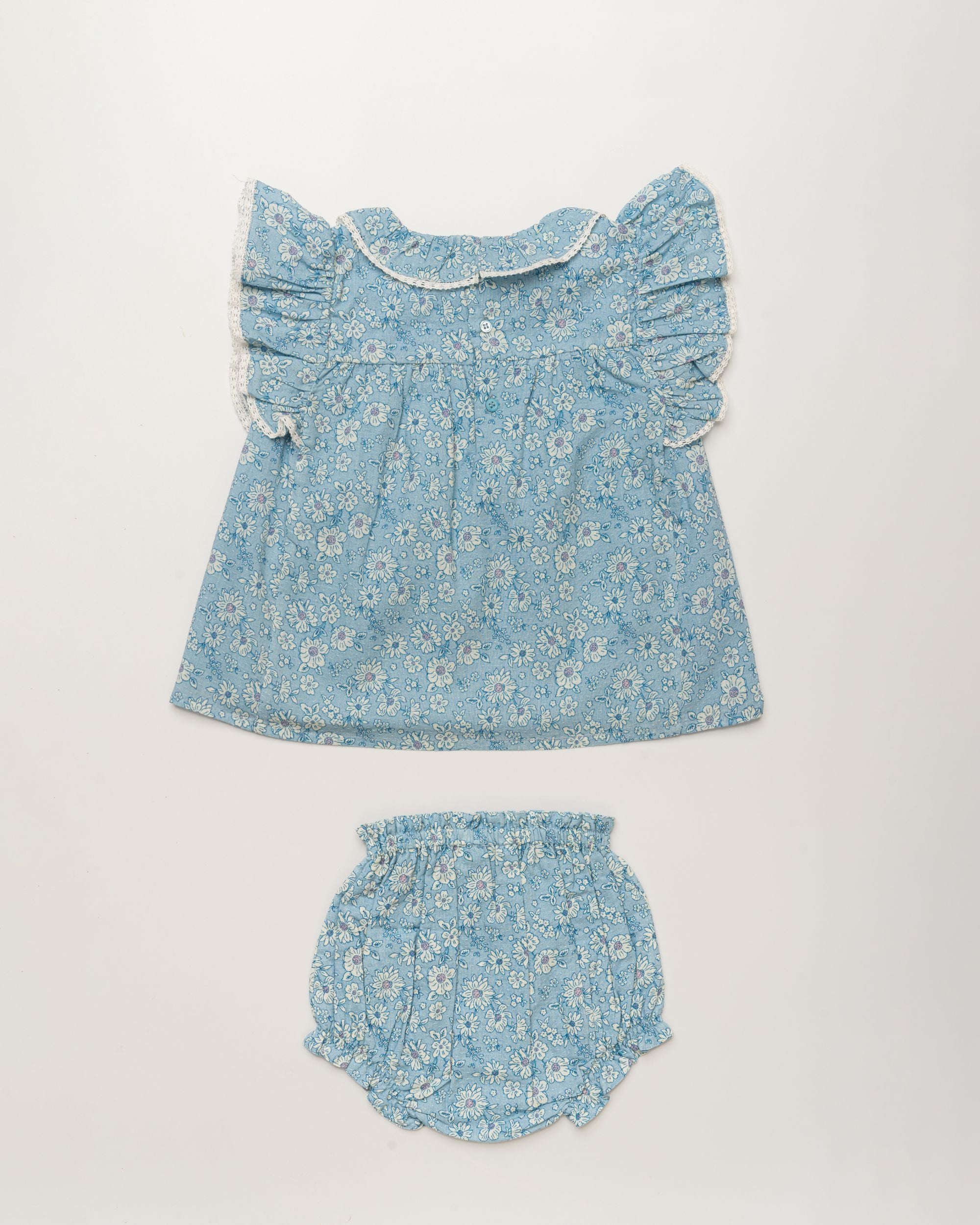 Early Sunday, Vicky Baby Dress & Bloomer Set in Tonal Floral Blue color, made from 100% Cotton Swiss Dobby Tiny Dots fabric, featuring a floral print with lace borders, shown in a back flat-lay view